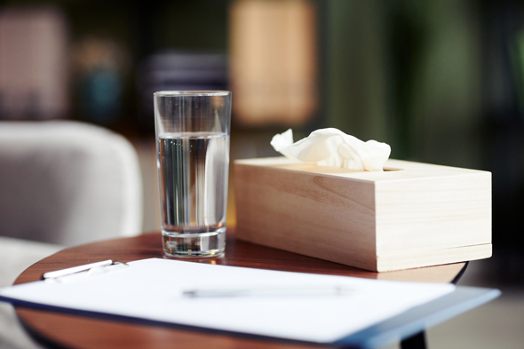 glass of water box of tissues and clipboard on wooden table